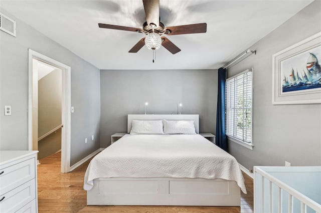 bedroom with light wood-style floors, baseboards, visible vents, and ceiling fan