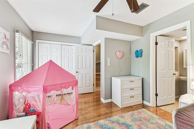 bedroom with baseboards, visible vents, a ceiling fan, light wood-style floors, and a closet