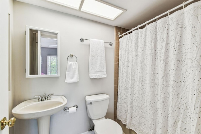 full bath featuring toilet, curtained shower, and a sink