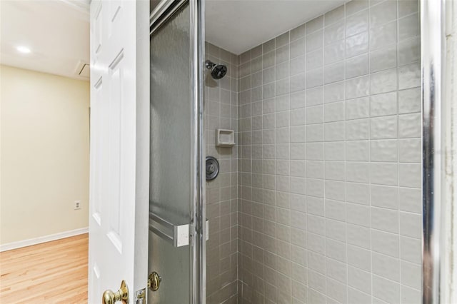 full bath featuring a stall shower, baseboards, and wood finished floors