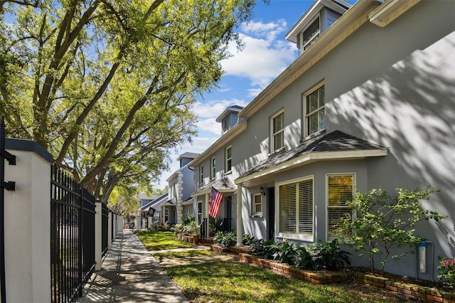 view of property exterior featuring stucco siding, fence, and a residential view