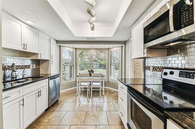 kitchen featuring stainless steel appliances, a sink, baseboards, and white cabinets
