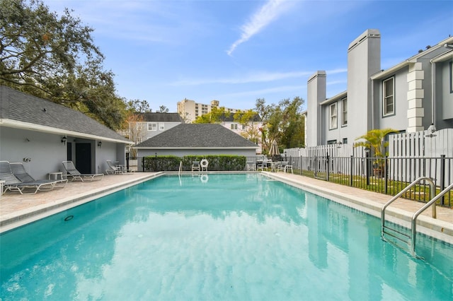 community pool featuring fence, a patio area, and a residential view