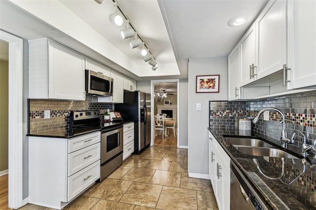 kitchen featuring stainless steel appliances, baseboards, a sink, and dark stone counters