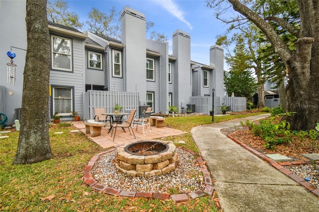view of home's community with a fire pit, a patio area, and fence
