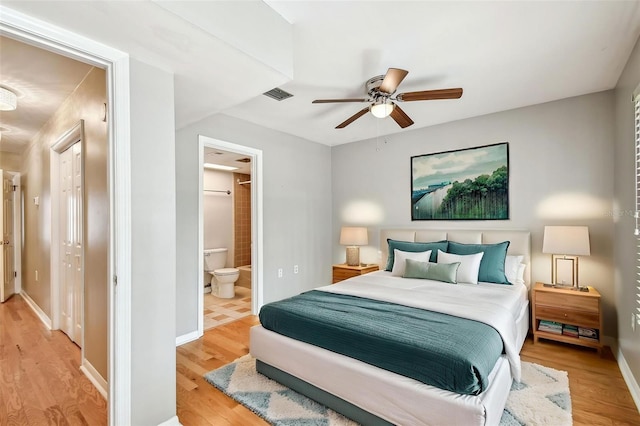 bedroom with light wood finished floors, ensuite bath, a ceiling fan, and baseboards
