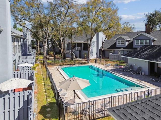 community pool featuring fence, a patio, and a residential view
