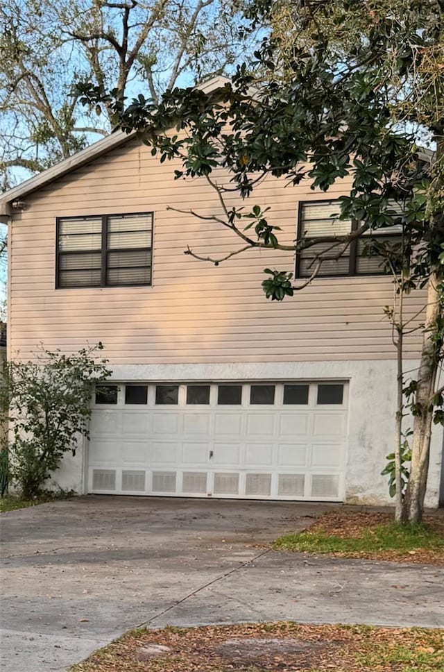 view of side of property with a garage, driveway, and stucco siding