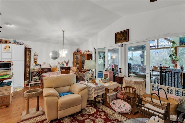 living area featuring lofted ceiling, light wood-type flooring, and a chandelier