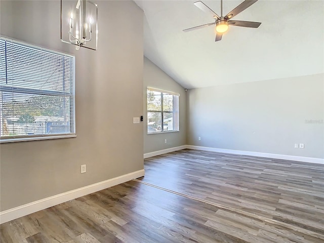 unfurnished room featuring ceiling fan with notable chandelier, vaulted ceiling, baseboards, and wood finished floors