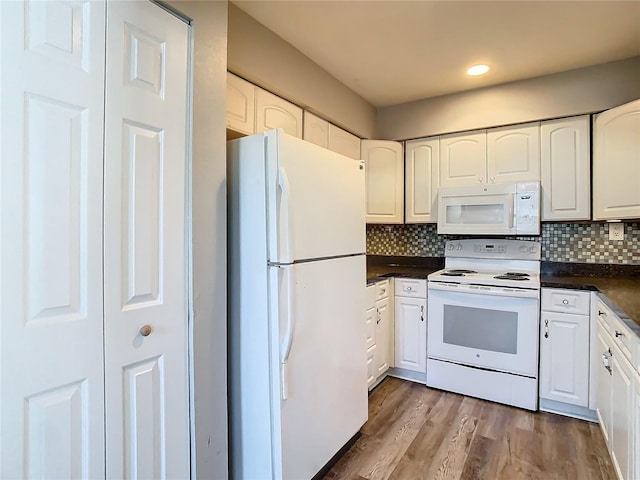 kitchen with dark countertops, decorative backsplash, white cabinets, light wood-type flooring, and white appliances