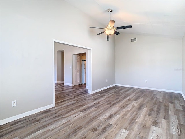 spare room featuring visible vents, a ceiling fan, wood finished floors, high vaulted ceiling, and baseboards