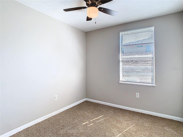 carpeted empty room featuring a wealth of natural light, ceiling fan, and baseboards