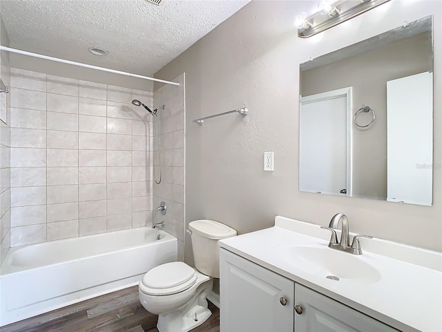 bathroom featuring bathing tub / shower combination, toilet, vanity, a textured ceiling, and wood finished floors