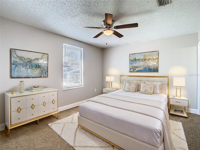 carpeted bedroom with a textured ceiling, baseboards, a ceiling fan, and visible vents