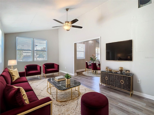 living room with ceiling fan, baseboards, vaulted ceiling, and wood finished floors