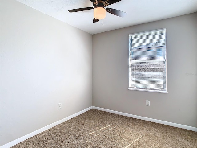 carpeted empty room featuring baseboards and a ceiling fan