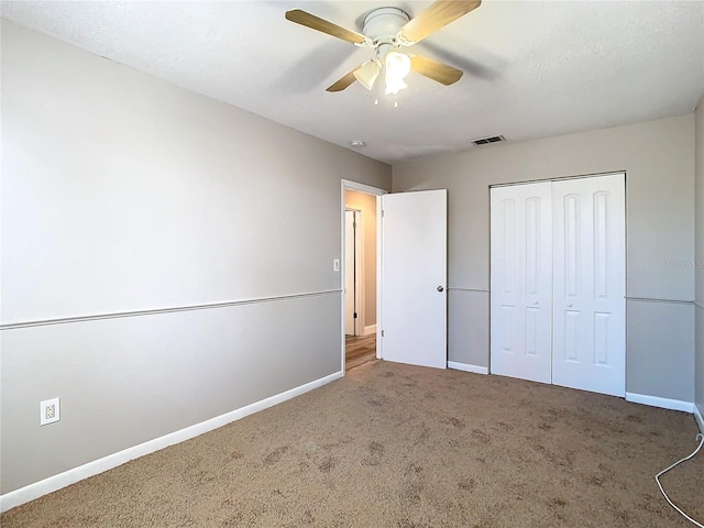 unfurnished bedroom with a closet, baseboards, visible vents, a ceiling fan, and carpet floors