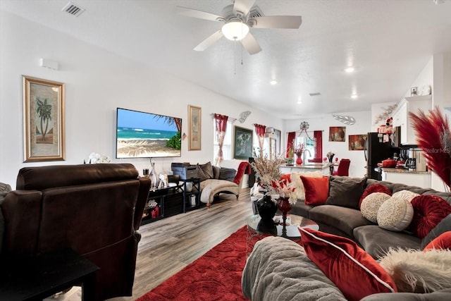 living room with light wood-type flooring, visible vents, and ceiling fan