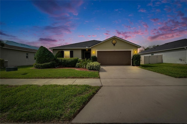 ranch-style house with an attached garage, fence, driveway, stucco siding, and a front yard