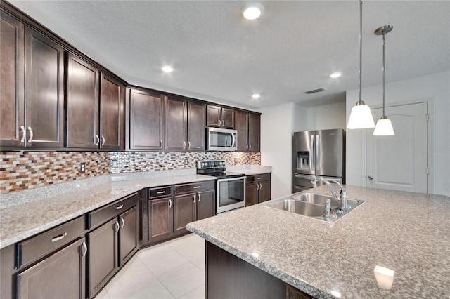 kitchen featuring dark brown cabinetry, a sink, visible vents, appliances with stainless steel finishes, and backsplash