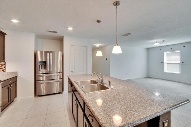 kitchen featuring visible vents, a sink, stainless steel refrigerator with ice dispenser, and an island with sink