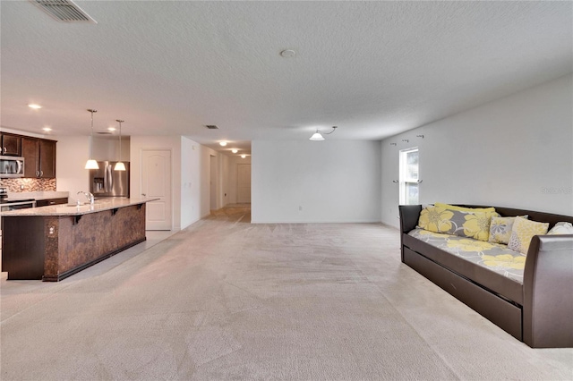 living room featuring visible vents, light carpet, and a textured ceiling