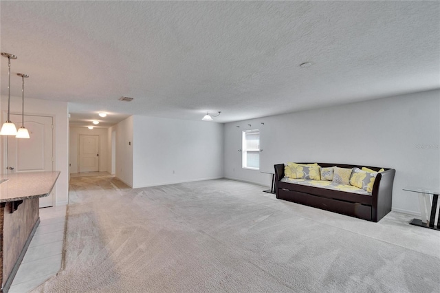 sitting room featuring a textured ceiling, baseboards, visible vents, and light colored carpet