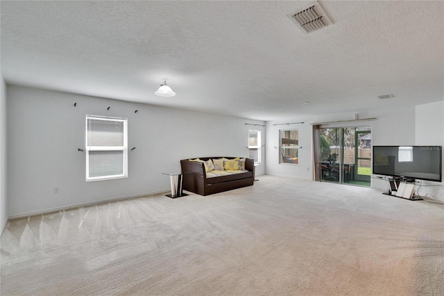 unfurnished room with carpet, visible vents, and a textured ceiling