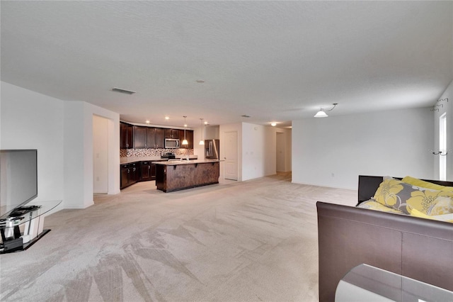 living area with visible vents, light carpet, and a textured ceiling