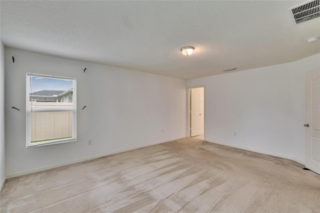 spare room featuring visible vents, a textured ceiling, and light colored carpet