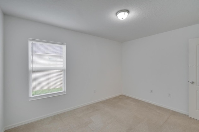 unfurnished room featuring light carpet, baseboards, and a textured ceiling