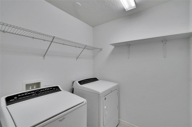 laundry area with washer and dryer, laundry area, a textured ceiling, and baseboards