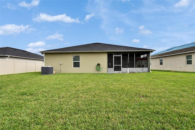 back of house with central air condition unit, fence, a sunroom, a lawn, and stucco siding