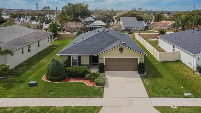 exterior space with a garage, concrete driveway, a fenced backyard, a residential view, and a front lawn