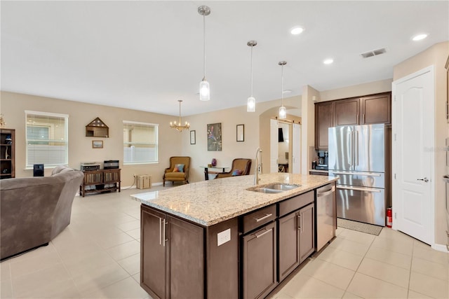 kitchen with dark brown cabinetry, visible vents, open floor plan, stainless steel appliances, and a sink