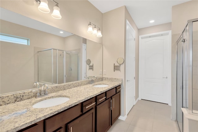 bathroom featuring double vanity, a stall shower, a sink, and tile patterned floors