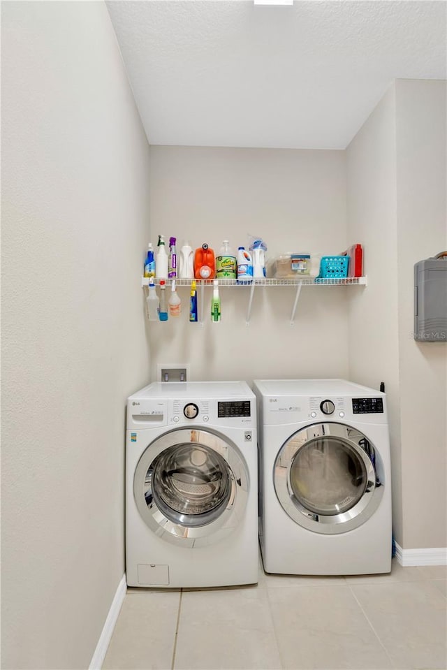 washroom featuring tile patterned flooring, laundry area, baseboards, and separate washer and dryer