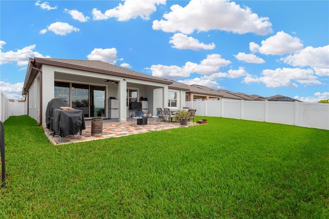 rear view of property featuring a yard, a fenced backyard, stucco siding, and a patio