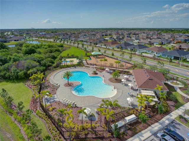 community pool with a patio area, fence, and a residential view