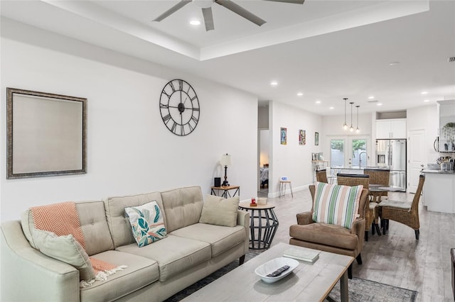 living room featuring a ceiling fan, recessed lighting, baseboards, and light wood finished floors