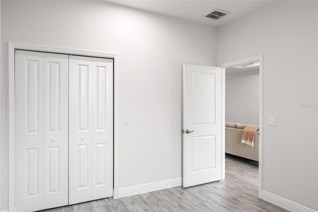 unfurnished bedroom with light wood-style flooring, a closet, visible vents, and baseboards