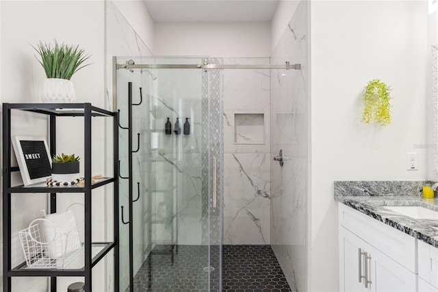 bathroom featuring a marble finish shower and vanity