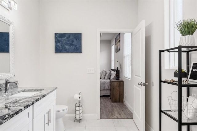 bathroom with baseboards, connected bathroom, toilet, tile patterned floors, and vanity