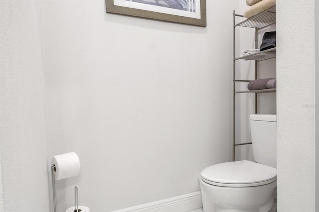 half bath with baseboards and toilet