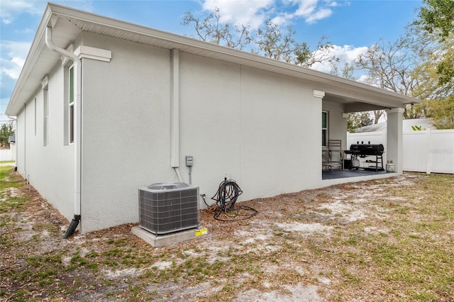 back of house with central AC unit, a patio area, fence, and stucco siding