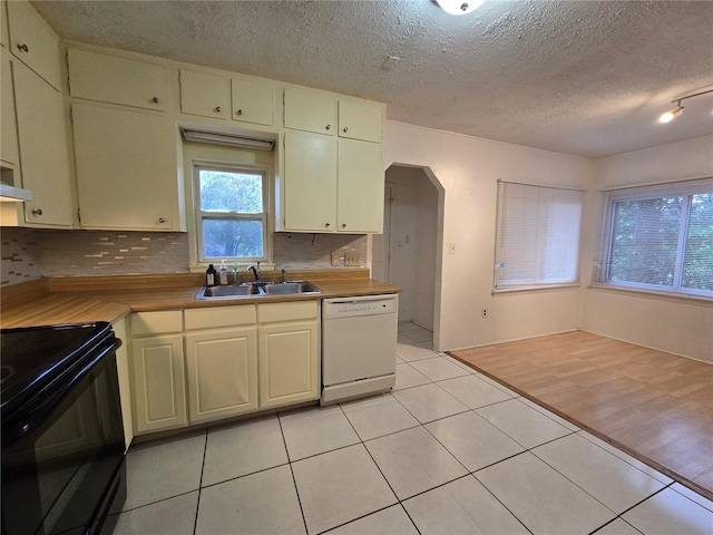 kitchen with arched walkways, a sink, light countertops, black electric range, and dishwasher