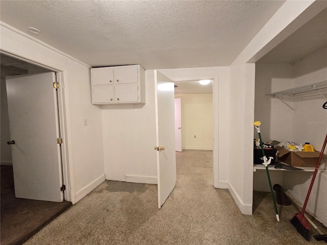 interior space featuring a textured ceiling, light carpet, and baseboards