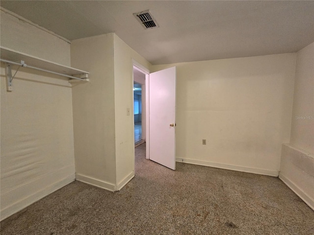 interior space featuring dark colored carpet, visible vents, and baseboards