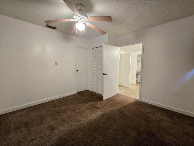 unfurnished bedroom featuring a textured ceiling, dark colored carpet, a closet, and a ceiling fan